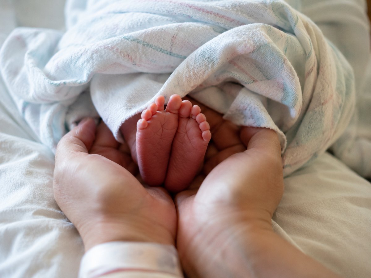 Primo piano sulle mani e piedi di un neonato in ospedale, luce naturale delicata