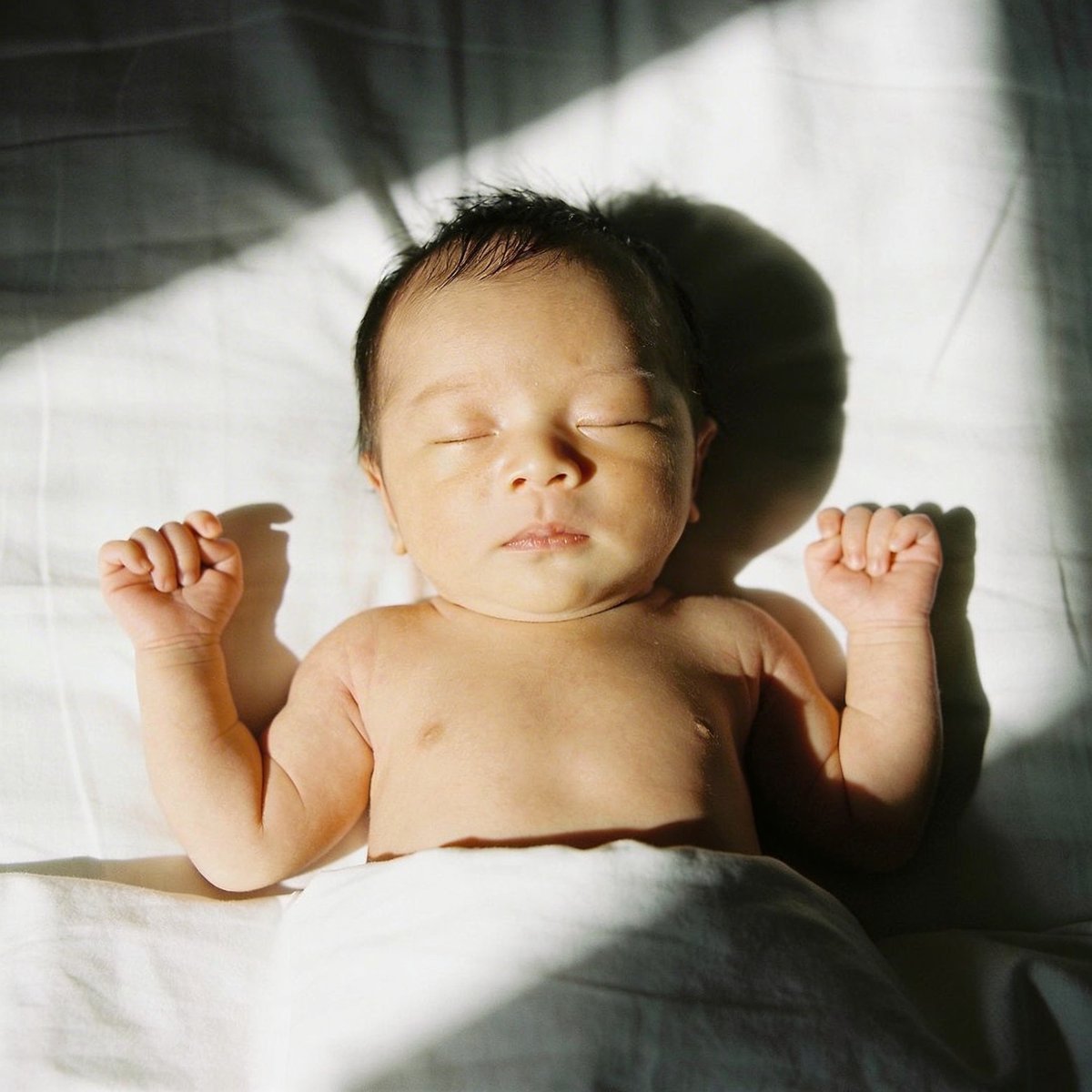 Neonato fotografato con luce naturale morbida vicino a una finestra a 45 gradi