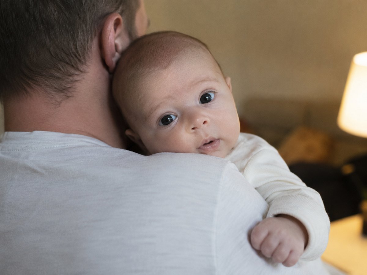 Neonato di 3 mesi sorridente tra le braccia dei genitori durante un servizio fotografico famiglia